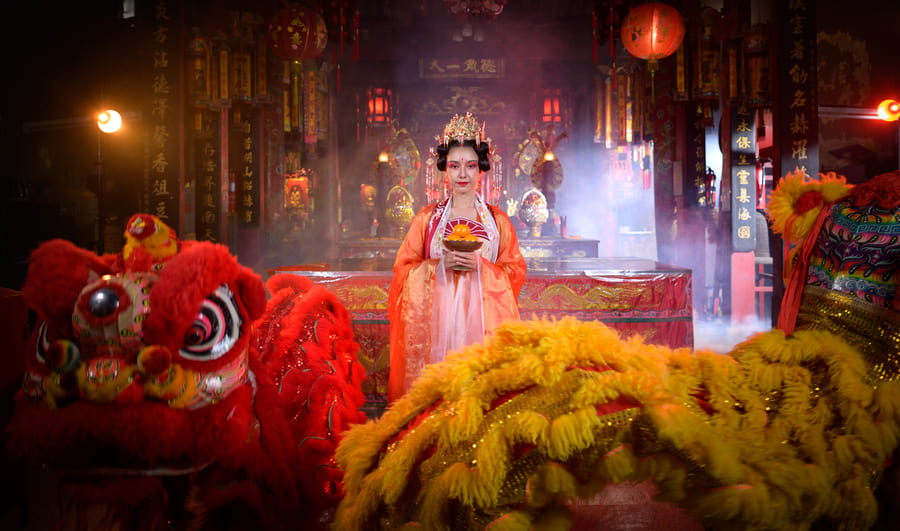 mijer vestida tradicionalmente con traje de musa china y trajes de leones chinos a sus pies