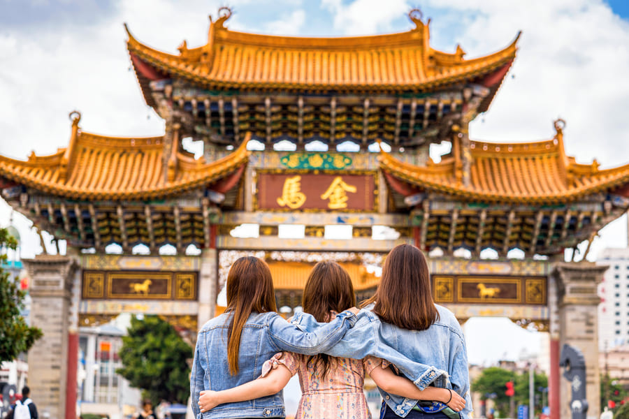 Templo chino de fondo y tres personas abrazadas admirandolo